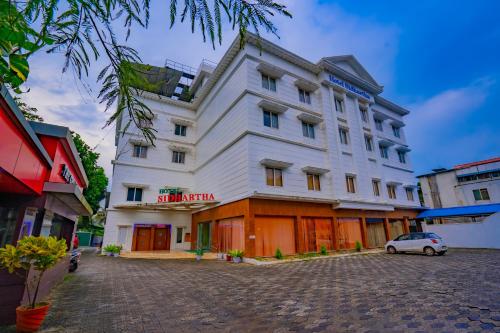a white building with a car parked in front of it at Hotel Sidhartha Chalakudy in Kizhake Chālakudi