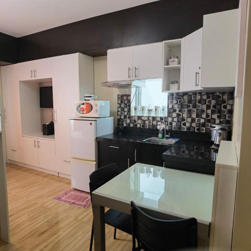 a kitchen with white cabinets and a table with chairs at Avida Davao by davaobnb & Lemonique Homes in Davao City
