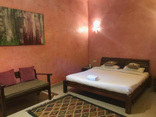 a bedroom with a bed and a chair at juSTa Morjim Beach Resort Goa - 80 Steps from Morjim Beach in Morjim