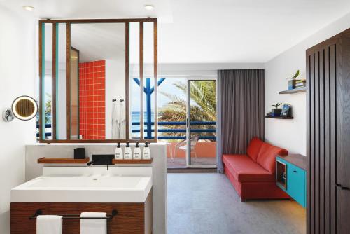 a bathroom with a sink and a red couch at Salt of Palmar, Mauritius, a Member of Design Hotels in Belle Mare