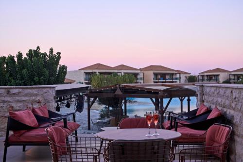 a patio with tables and chairs with a view of the ocean at Atlantica Aegean Park in Kolimbia