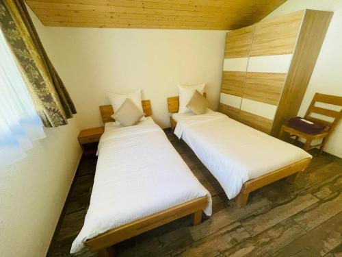 two beds in a small room with a chair at Swiss Chalet Holidays Ringgenberg in Ringgenberg