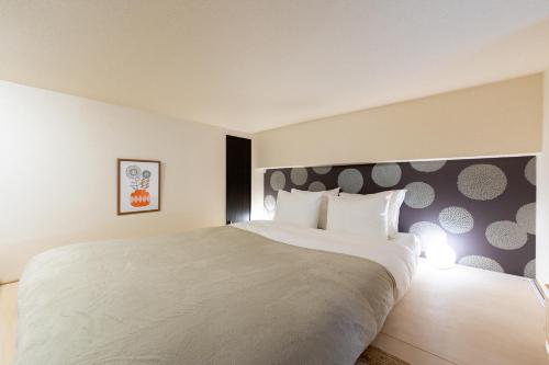 a bedroom with a large white bed with a wall at Home Sweet Office Kamata in Tokyo