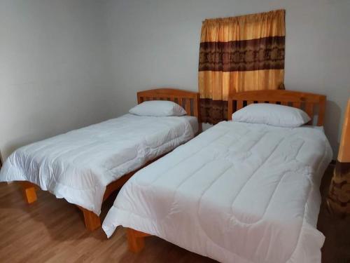 Cette chambre comprend 2 lits avec des couvertures et des oreillers blancs. dans l'établissement ริมทุ่งโฮมสเตย์, à Ban Pa Tiu