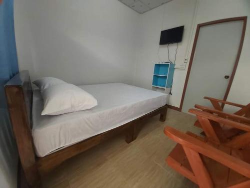 um pequeno quarto com uma cama e uma cadeira em ริมทุ่งโฮมสเตย์ em Ban Pa Tiu