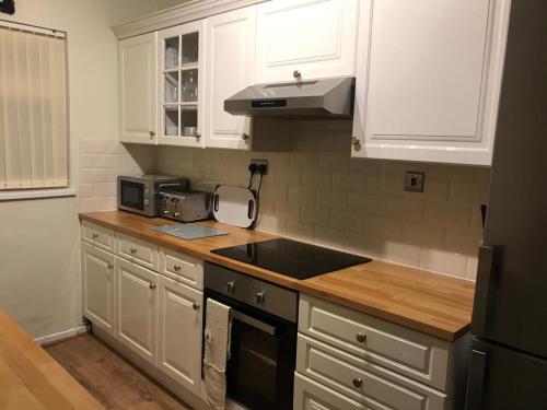 a kitchen with white cabinets and a black sink at Snowdonia miners cottage in Blaenau-Ffestiniog