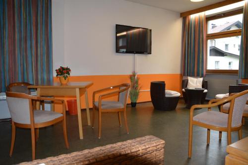 a waiting room with a table and chairs and a tv at Jugendherberge Bad Gastein in Bad Gastein