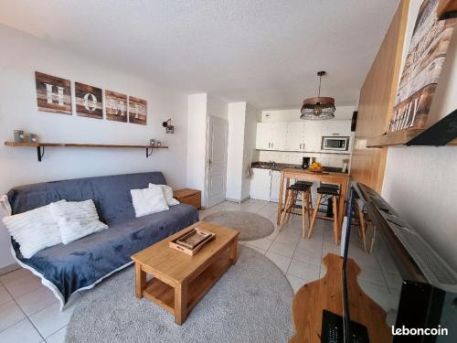 a living room with a blue couch and a table at Appartement T2-5 couchages L'écrin des Orres 1800 in Les Orres