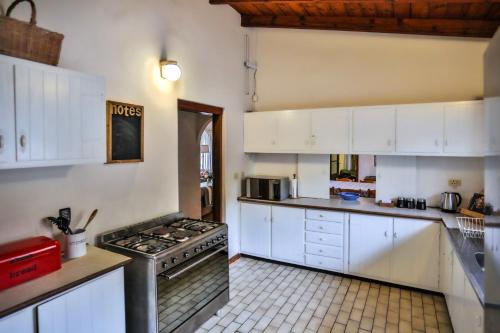 a kitchen with white cabinets and a stove top oven at One Jack Powell House- Classic family home steps away from the beach in Ballito