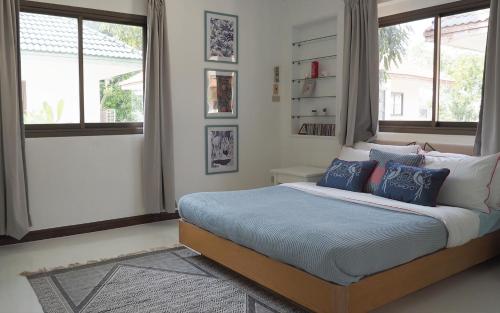1 dormitorio con 1 cama con almohadas y ventanas azules en Rayong Beach House en Ban Bang Nok