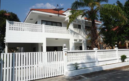 a white fence in front of a white house at Rayong Beach House in Ban Bang Nok