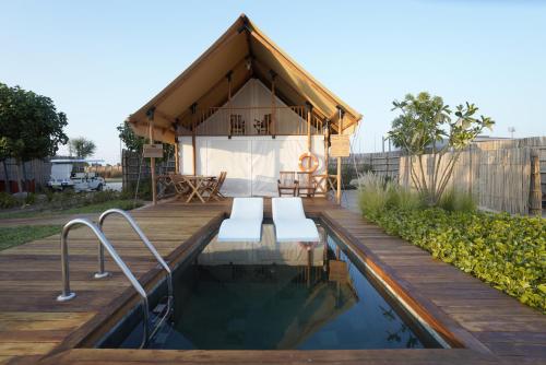 a small house with a pool and a wooden deck at Bab Al Nojoum Hudayriyat Camp in Abu Dhabi