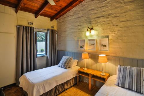 a bedroom with two beds and a table with two lamps at One Jack Powell House- Classic family home steps away from the beach in Ballito