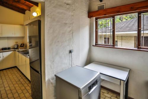 a small kitchen with a refrigerator and a window at One Jack Powell House- Classic family home steps away from the beach in Ballito