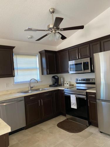 a kitchen with brown cabinets and a ceiling fan at __Kristian’s Palace Your Beach Getaway in Kill Devil Hills