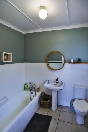 a bathroom with a sink and a tub and a toilet at One Jack Powell House- Classic family home steps away from the beach in Ballito