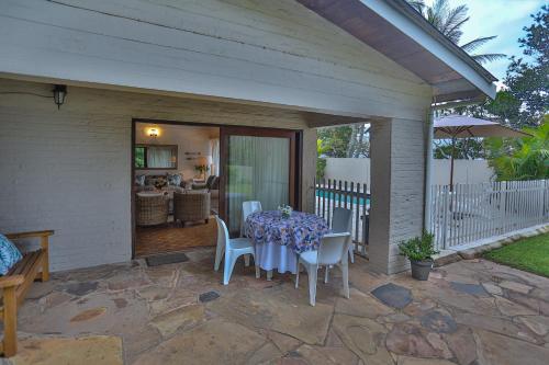 a patio with a table and chairs on it at One Jack Powell House- Classic family home steps away from the beach in Ballito