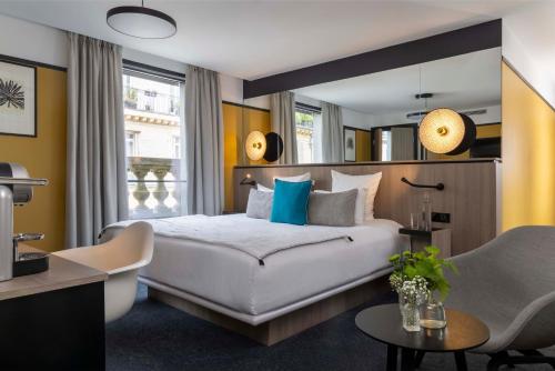 sypialnia z dużym białym łóżkiem i krzesłem w obiekcie Hôtel Opéra Liège w Paryżu