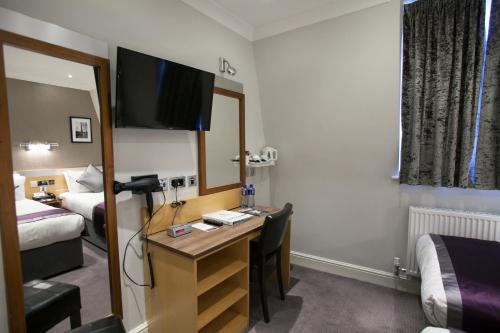 a hotel room with a desk and a mirror at Best Western Chiswick Palace & Suites London in London