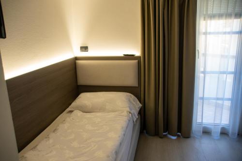 a small bed in a room with a window at Hotel Garnì Villa Fontana in Trento