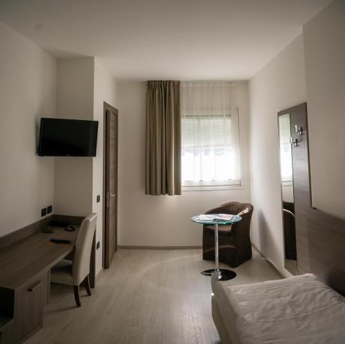 トレントにあるホテル ガルニ ヴィラ フォンタナのベッド、デスク、テーブルが備わる客室です。
