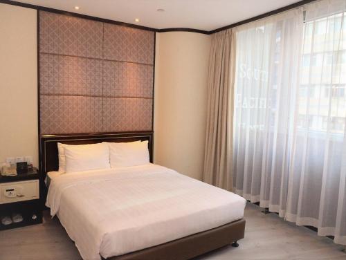 a bedroom with a bed and a large window at South Pacific Hotel in Hong Kong