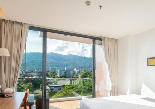 a bedroom with a bed and a large window at Eastin Tan Hotel Chiang Mai in Chiang Mai