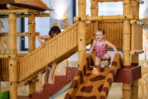two young girls playing on a wooden play structure at Alpholiday Dolomiti Wellness & Family Hotel in Dimaro