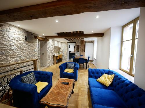 a living room with blue couches and a stone wall at Gîte de Crémieu in Crémieu