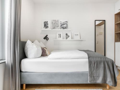 a bedroom with a bed with white walls and a mirror at Limehome Augsburg Am Katzenstadel in Augsburg