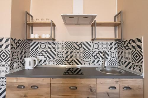 uma cozinha com um lavatório e azulejos pretos e brancos em Pivdenniy em Lviv