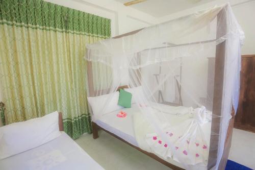 a bedroom with a bed with a canopy at Dinuda Resort in Kalpitiya