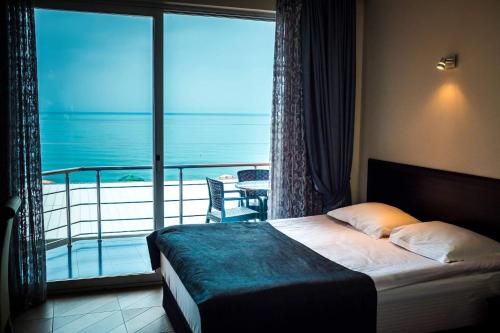 a bedroom with a bed with a view of a balcony at Hotel Neptun Kvariati in Kvariati