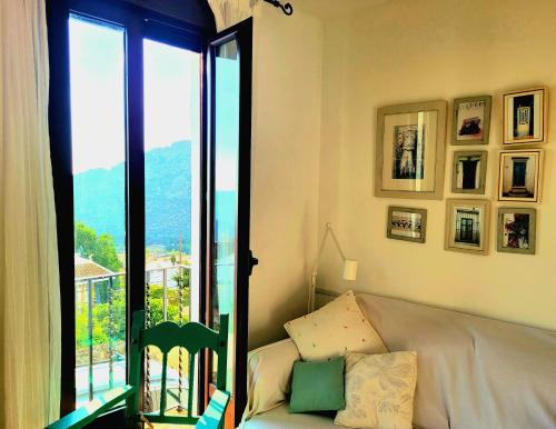 ein Wohnzimmer mit einem Sofa und einem großen Fenster in der Unterkunft Luminoso con vistas y chimenea apto mascotas in Benaocaz