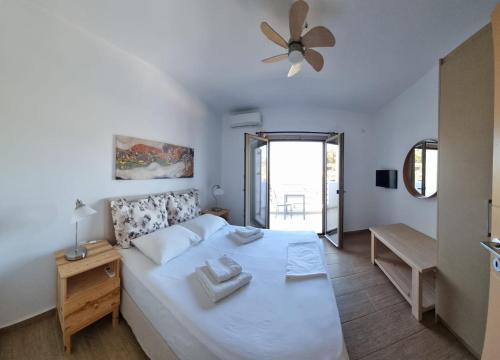 ein Schlafzimmer mit einem weißen Bett mit Deckenventilator in der Unterkunft Skiathos Lagoterra Apartments in Skiathos-Stadt