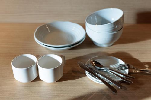 a table topped with white cups and forks and spoons at ORI Kyoto in Kyoto
