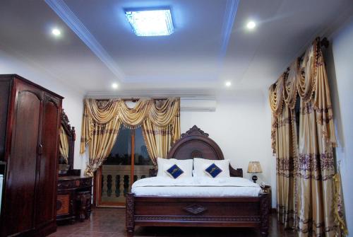 Schlafzimmer mit einem Bett und einem Fenster mit Vorhängen in der Unterkunft Emerald BB Battambang Hotel in Battambang