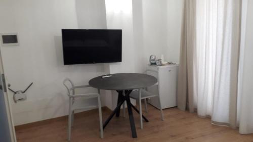 a room with a table and a television on a wall at I Faraglioni Comfort Rooms in Terrasini