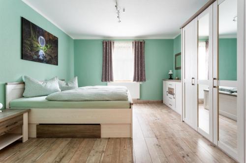 a bedroom with green walls and a bed with a wooden floor at Ferienwohnung Julia Unterweißbach in Unterweißbach