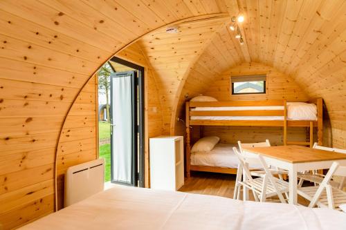 Camping Pods Hedley Wood Holiday Park في Bridgerule: غرفة بسرير وطاولة في كابينة