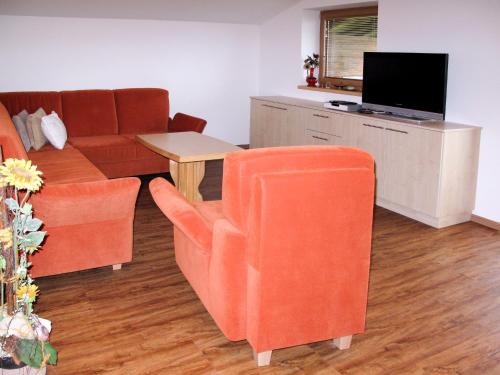sala de estar con sillas de color naranja y sofá en Apartment Tauernblick - BMG190 by Interhome, en Bramberg am Wildkogel