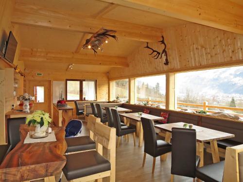 a dining room with tables and chairs and windows at Chalet Talbach - MHO778 by Interhome in Laimach