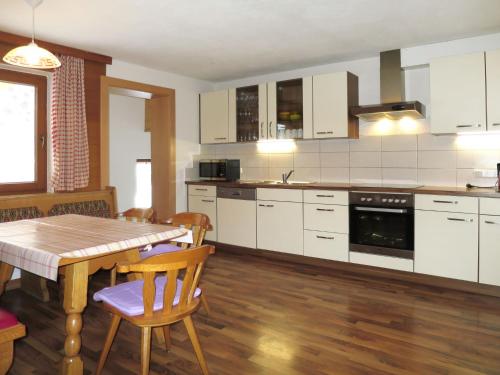 マイヤーホーフェンにあるHoliday Home Rieplerhof - MHO157 by Interhomeの白いキャビネット、テーブルと椅子付きのキッチンが備わります。