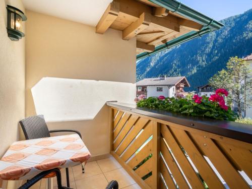 un balcón con una mesa, una silla y flores en Apartment Rosa - MHO134 by Interhome en Mayrhofen