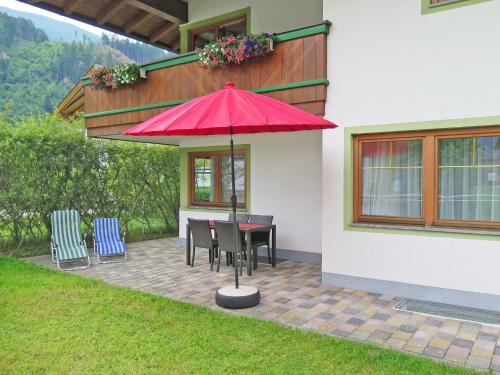 eine Terrasse mit einem Tisch, Stühlen und einem Sonnenschirm in der Unterkunft Apartment Haus Sonne - ZAZ681 by Interhome in Aschau