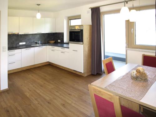 una cocina con armarios blancos y una mesa con comedor. en Apartment Anton - MHO561 by Interhome, en Ramsau im Zillertal
