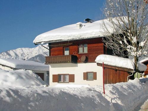 a house covered in snow in front of a mountain at Apartment Peter by Interhome in Waidring