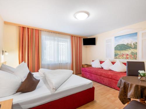 a hotel room with two beds and a red couch at Apartment Rosa-3 by Interhome in Mayrhofen