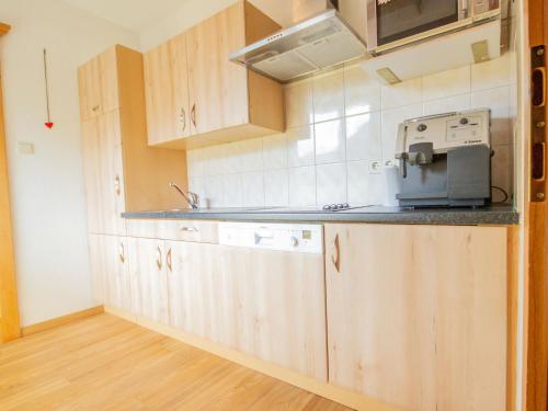 cocina con armarios de madera y microondas en Apartment Weinberg by Interhome, en Pettneu am Arlberg