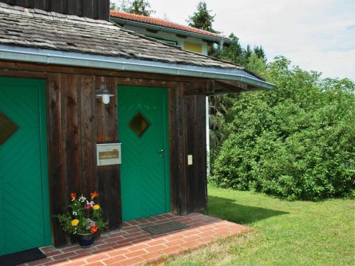 a wooden shed with a green door and flowers at Holiday Home kleine Winten by Interhome in Geinberg